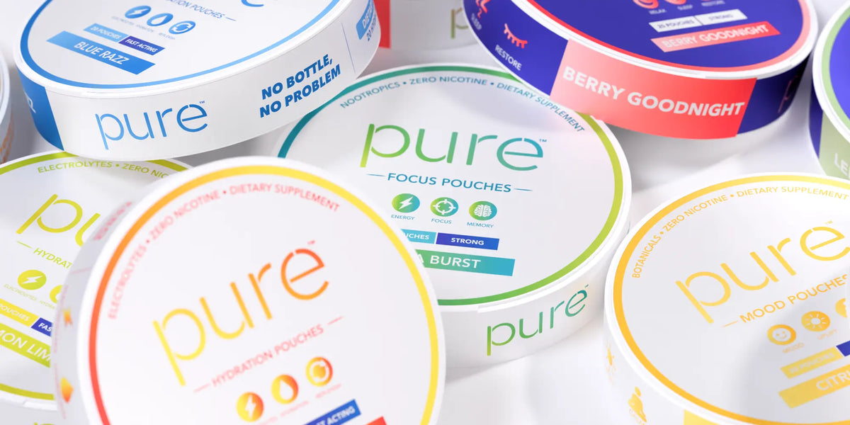 Several round Pure dietary supplement focus pouch containers arranged closely together on a white background. Visible flavor/variant text includes Berry Goodnight, Mood Pouchie, and others, with the brand name pure prominently printed on the lids.